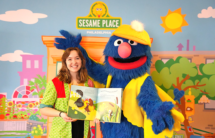 Grover and a Sesame Place Ambassador reading a storybook