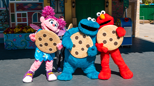 Abby, cookie, and elmo all with a big cookie.