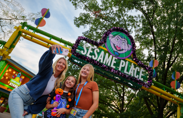 Three people in front of gate with Halloween merchandise