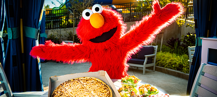 A pizza in a box next to salads