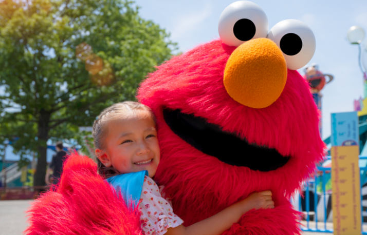 Elmo huggjng little girl.