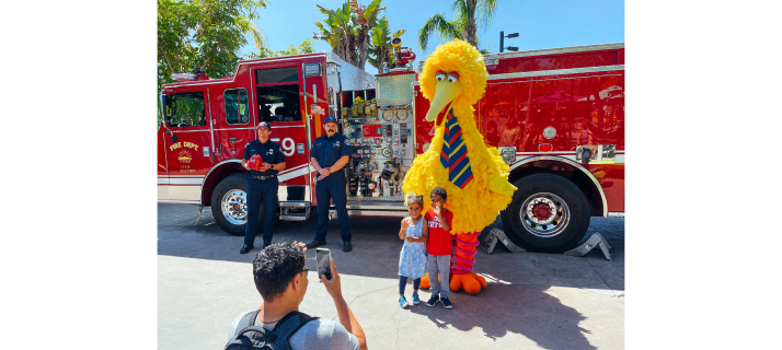 big bird with children in front of firetruck.